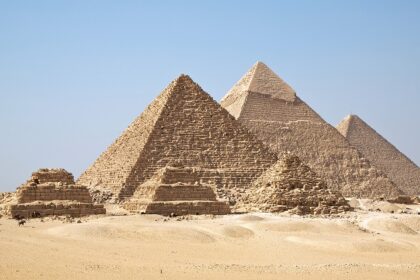 Giza Pyramids are standing tall on the rough, sandy landscape of a desert in Egypt.