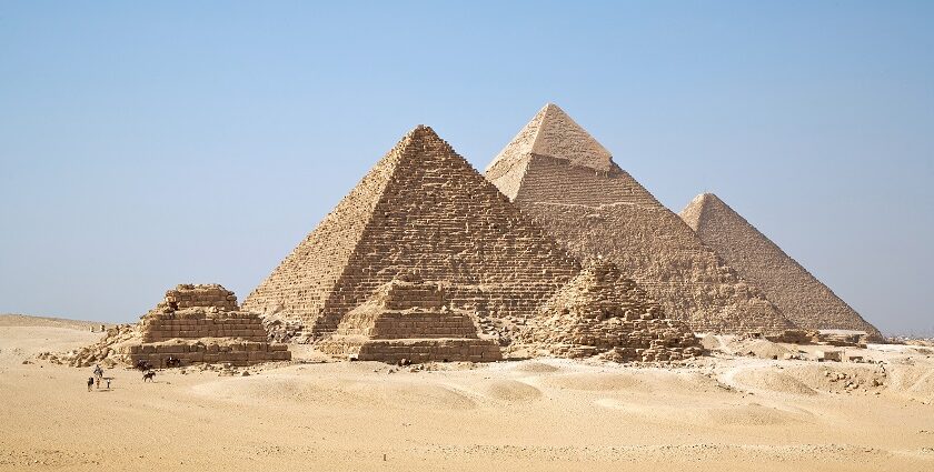 Giza Pyramids are standing tall on the rough, sandy landscape of a desert in Egypt.