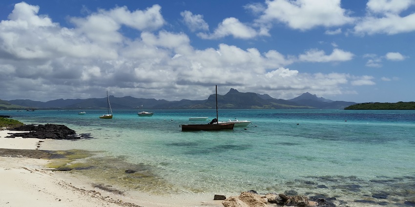 Beautifully photographed image of the Pointe d’Esny Beach in Mauritius with boats near the shore.