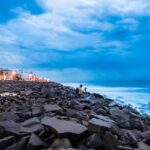 A man sets up his camera to take shots near a rocky beach in Pondicherry Harbour, India