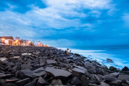 A man sets up his camera to take shots near a rocky beach in Pondicherry Harbour, India