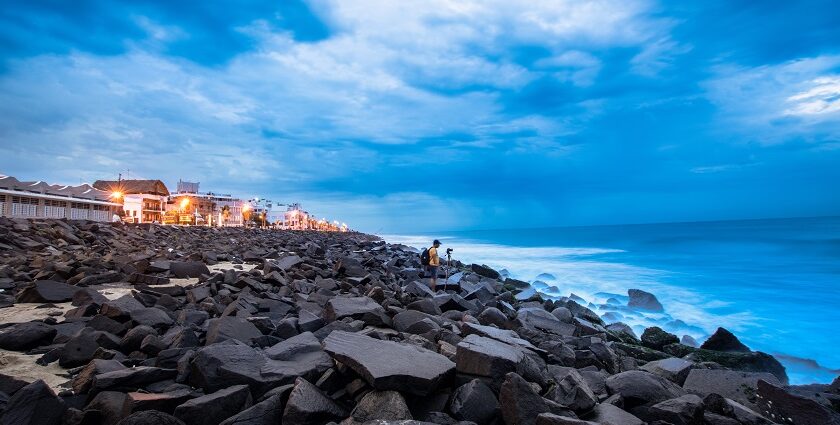 A man sets up his camera to take shots near a rocky beach in Pondicherry Harbour, India