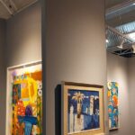 Vibrant artwork displayed in a modern gallery with visitors admiring the exhibits.