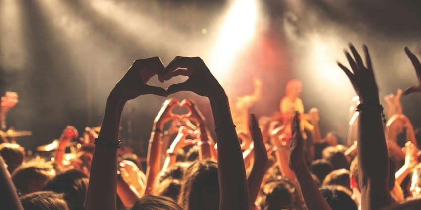 Image of music festival lovers enjoying the music and dancing at a festival with their hands raised