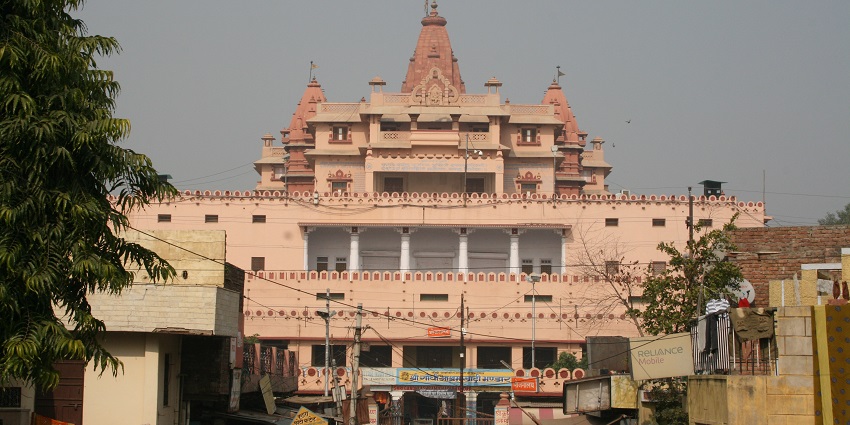 An image of Radha Vallabh Temple with a dome-like structure along with trees inside.