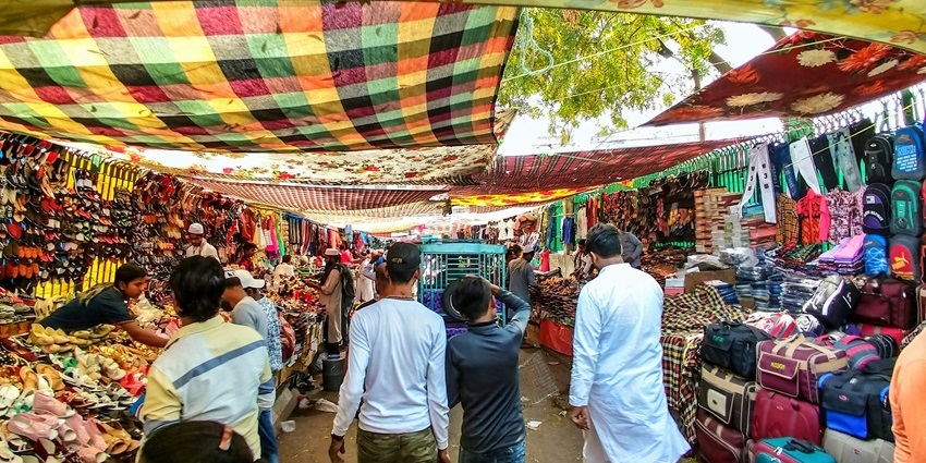 A picture of shoppers moving through a market’s lanes with numerous stalls all around