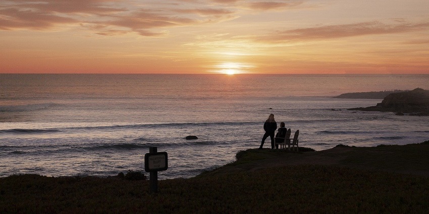 A stunning image of sunset over the ocean with cliffs and the coastline of Big Sur, California