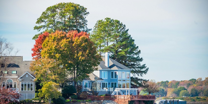 An image of a serene lakeside house surrounded by autumn foliage with large windows overlooking the lake.