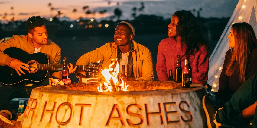 A group of friends sitting near the bonfire and singing songs and playing guitar, displaying Mauritius nightlife.