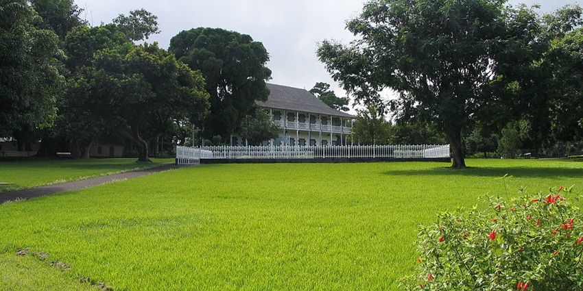 Green landscape with trees and a building in Sir Seewoosagur Ramgoolam Botanical Garden.