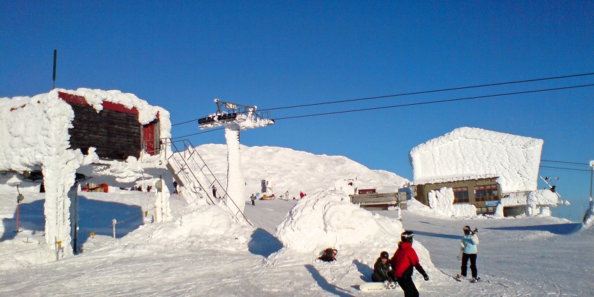 People enjoy snow activities on the top of the Area with snow-covered structures.