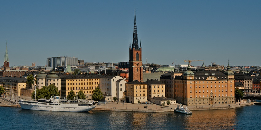 Tessin Palace with a flag on top standing next to other buildings in Gamla Stan town.