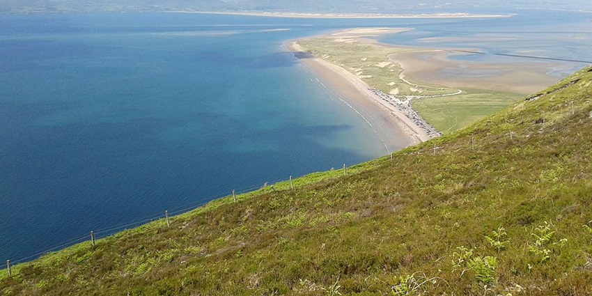 An image of Rossbeigh Beach in County Kerry, Ireland, featuring its sandy shore and stunning views
