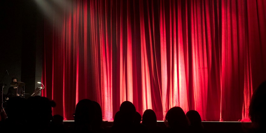 An image of a group of people seated in a theatre, watching a performance on stage in Seattle
