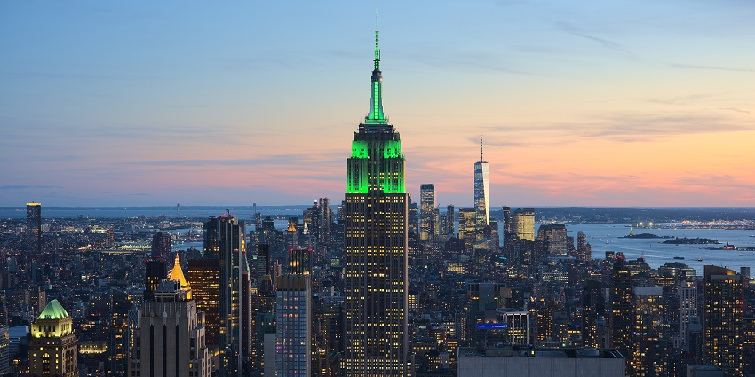 Empire State Building in the evening with the illuminated top of the building and lit city.
