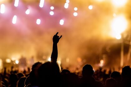 Crowd at a concert enjoying music with vibrant stage lights in the background.