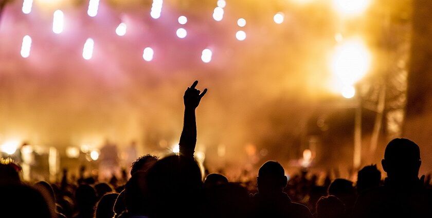 Crowd at a concert enjoying music with vibrant stage lights in the background.