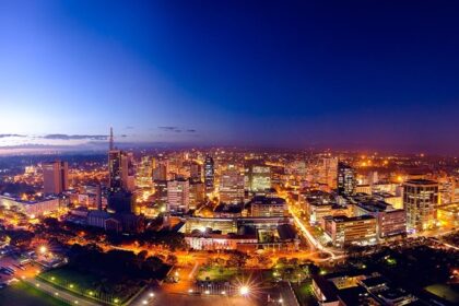 Nairobi city skyline at night with illuminated tall skyscrapers and roads under blue sky