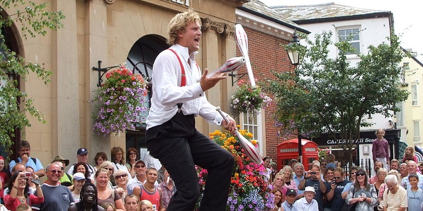 An image of a street performer juggling clubs in one of the most important festivals in England