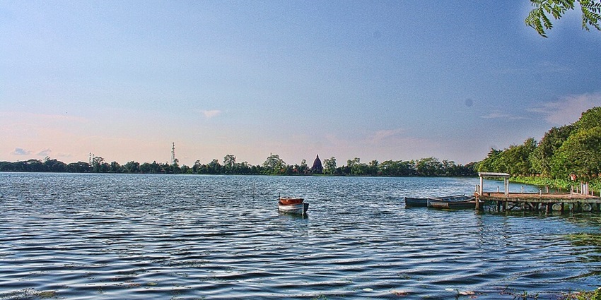A boat floating in the crystal blue waters of Sivasagar Tank, a sacred pond in Assam