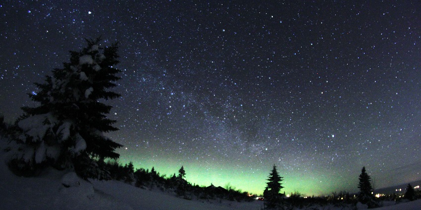 Stargazing at the night sky with Northern lights visible from Trysil covered in snow