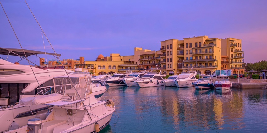 Some white motorboats are resting at a marina in Hurghada during a colorful sunset.