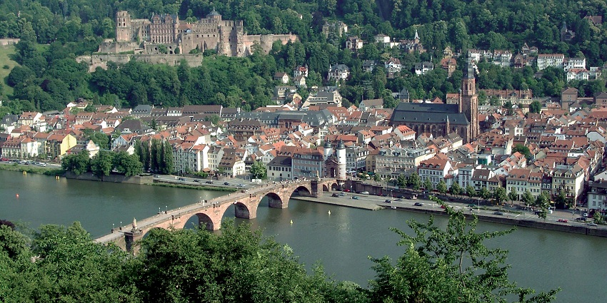 Heidelberg town visible from afar with a bridge and the old town surrounded by greenery.