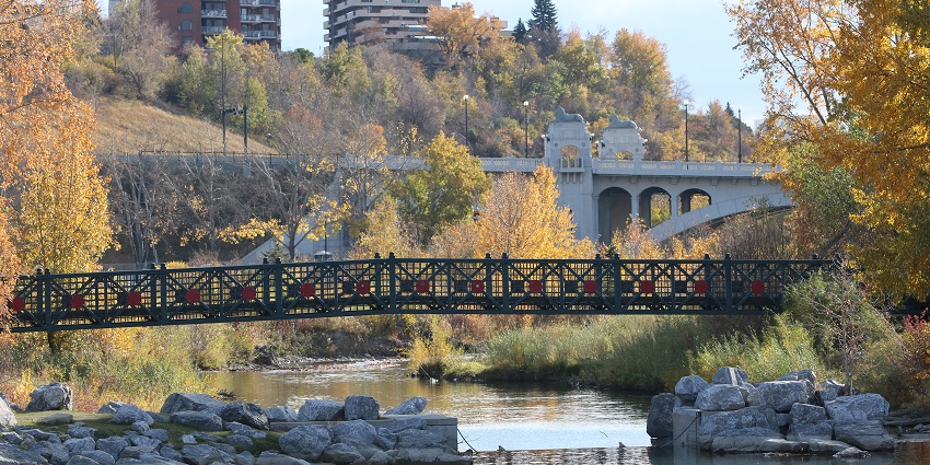 Prince’s Island Park with a bridge over the Bow River, autumn seasonal trees and buildings