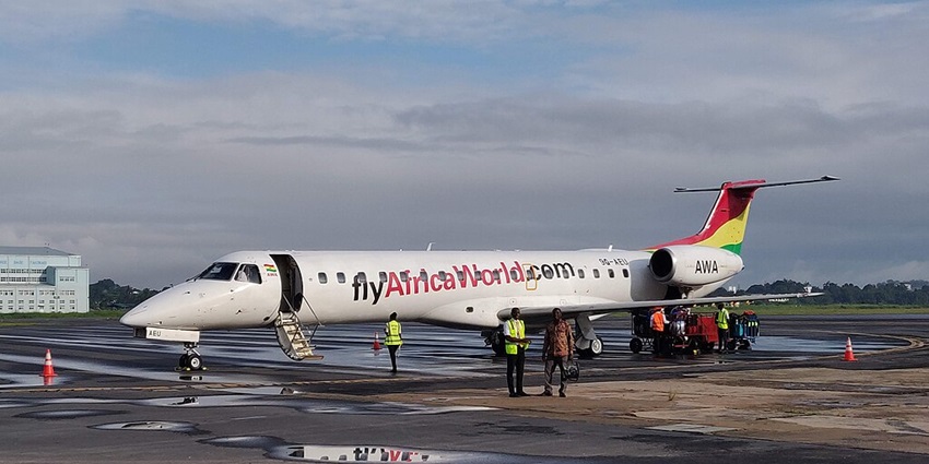 A passenger plane parked on the airport runway showing white clouds in the sky above.