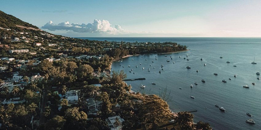 Tamarin Beach with several boats on the water, a town with greenery and a distant hill.