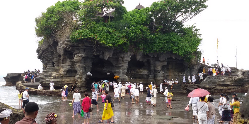 View of Tanah Lot Temple, surrounded by the sea, a place to visit on the Bali travel guide.
