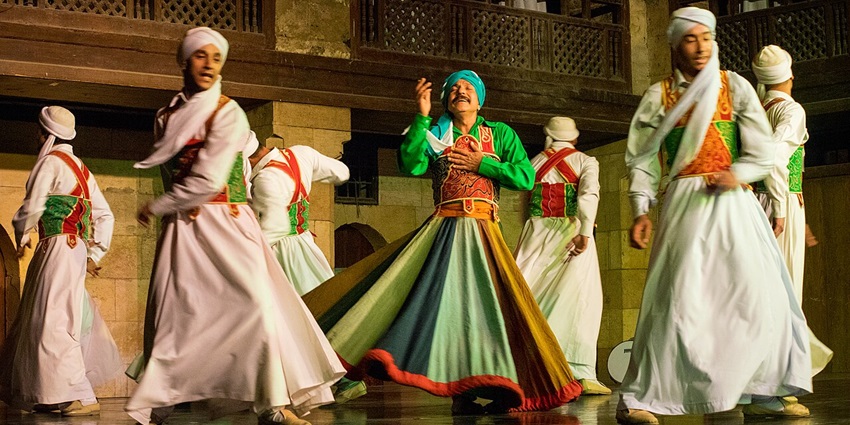 Tannoura dancers performing on the stage in green and white traditional folk dresses