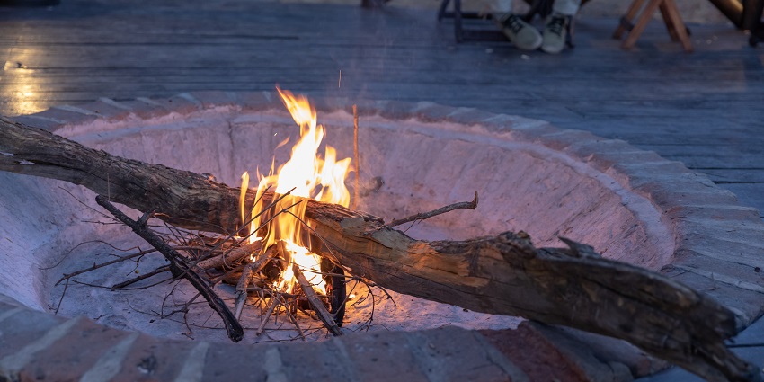 Small campfire made in a hollow circle and a person’s legs visible in the background.
