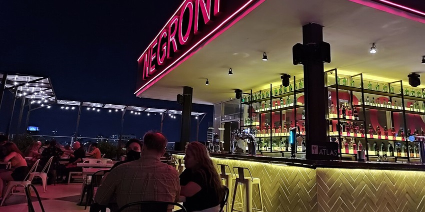 Rooftop bar with people sitting on the chairs and a bar counter in the background