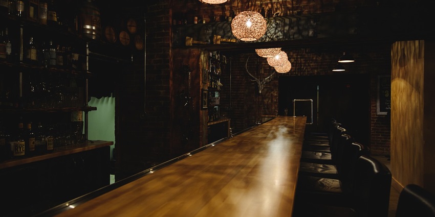 Bar counter with a wooden table, black chairs and unique lamps hanging from the ceiling