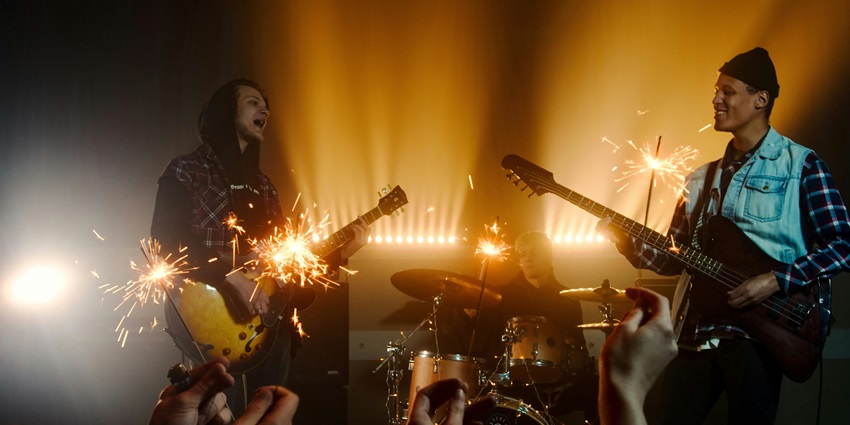A band performing with two guitarists singing and playing and a drummer in the background