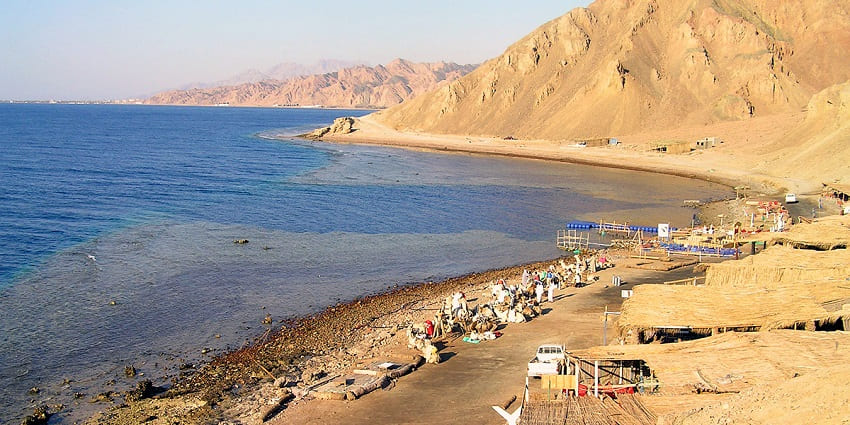 The blue hole in Dahab with people getting ready for scuba diving and distant mountains