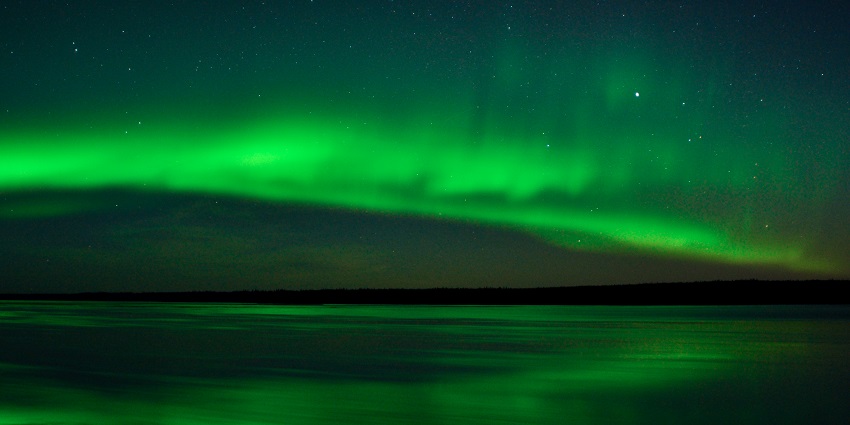 Aurora borealis glowing over La Grande River in Chisasibi, the best New Year event in Canada.