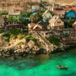 A view of Popeye Village, Mellieha, Malta showing several tiny houses and the sea around.