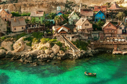 A view of Popeye Village, Mellieha, Malta showing several tiny houses and the sea around.