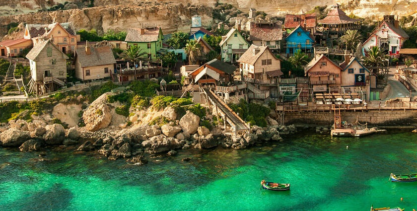 A view of Popeye Village, Mellieha, Malta showing several tiny houses and the sea around.