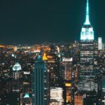 New York City at night with vibrant and brightly illuminated tall skyscrapers buildings.