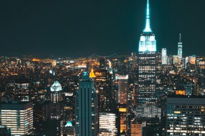 New York City at night with vibrant and brightly illuminated tall skyscrapers buildings.