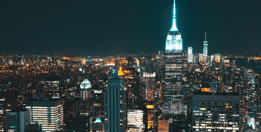 New York City at night with vibrant and brightly illuminated tall skyscrapers buildings.