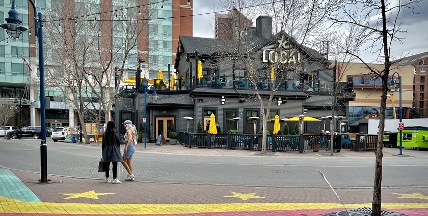 Two women standing on a painted pathway opposite the local pub eatery restaurant