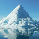 A clear reflection of a massive iceberg can be seen on the calm waters in Greenland.