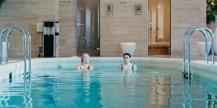 An image of an elderly and a young woman taking a cold plunge together in a swimming pool.