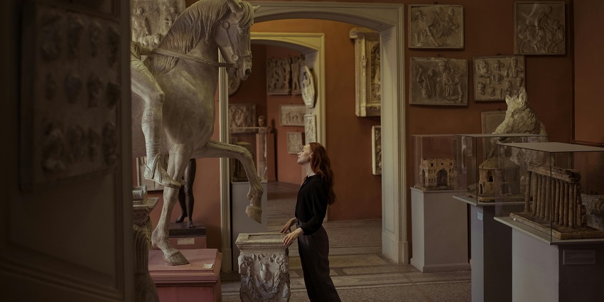 A woman looking at the sculpture of a horse in one of the museums like the Karmarkar Museum.