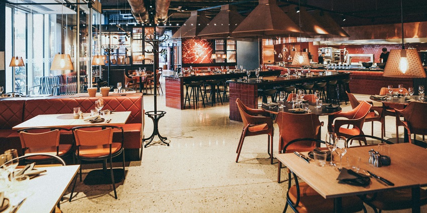 A picture of the interiors of a restaurant with wooden tables and chairs arranged for visitors