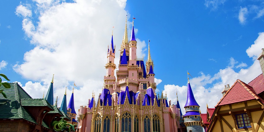 Walt Disney World Resort showcasing mountains and tip of a castle with few people at the gate